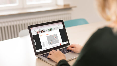 Photo of a female student sitting at a laptop where a video conference is open. __<br>Female student looks at the screen of the laptop where a video conference is open.