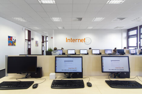 Photo of several computer workstations in the library reading room, some of them used by students__Photo of the computers in the library reading room, some of them used by students