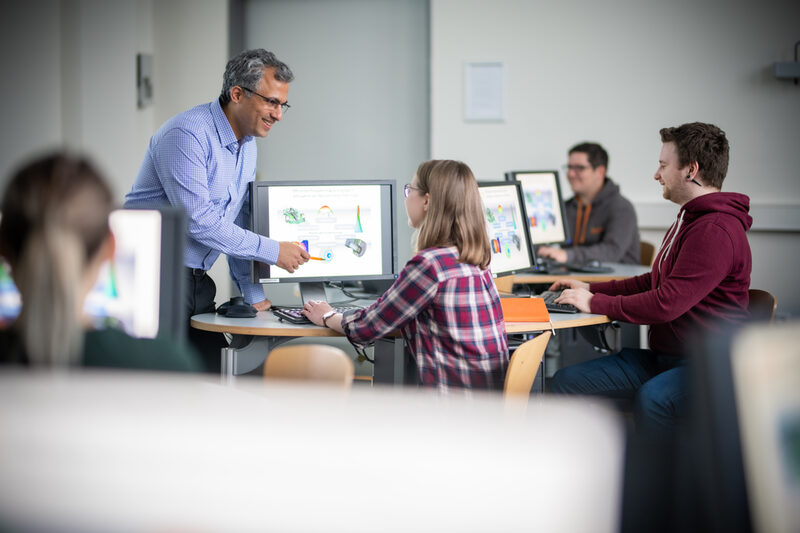 Foto einer Vorlesung des Fachbereichs Machinenbau. Ein Dozierender erklärt Studierenden eine technische Zeichnung an einem Bildschirm.__Photo of a lecture of the Department of Mechanical Engineering. A lecturer explains a technical drawing to students on a screen.