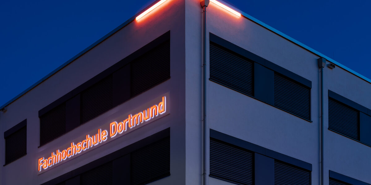 Foto vom bei Nacht leuchtendem Logo "Fachhochschule Dortmund" am Gebäude 38b.