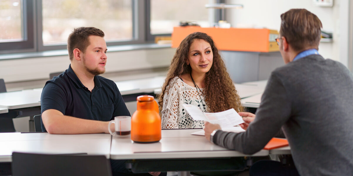 Photo of a counseling situation between two people seeking advice and a professional.