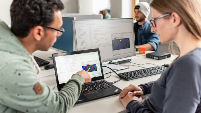 Photo of an employee showing his colleague something on his laptop.