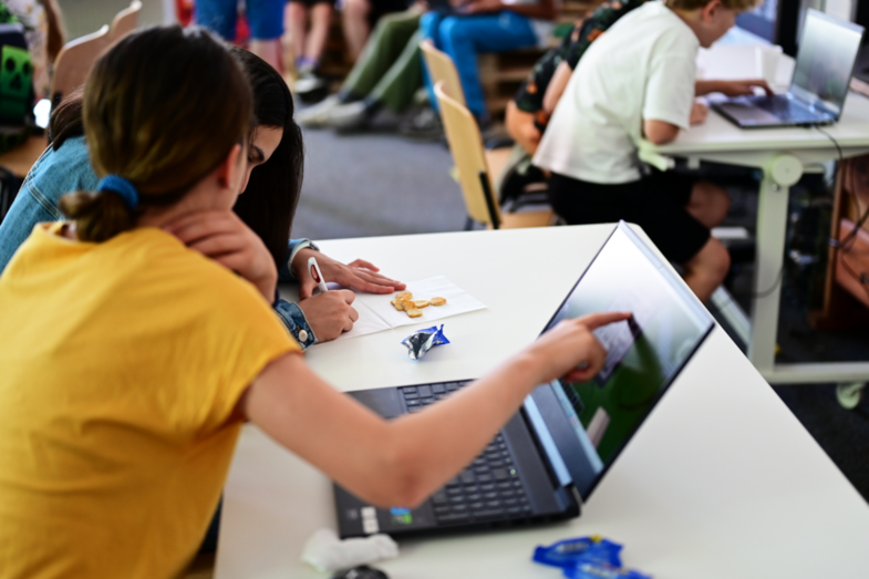 Two students sit in front of a notebook and draw an algorithm on a platter.