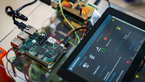 Detailaufnahme von einer Roboteraufbaute mit Platinen und einem Tablet, auf dem eine Software geöffnet ist.