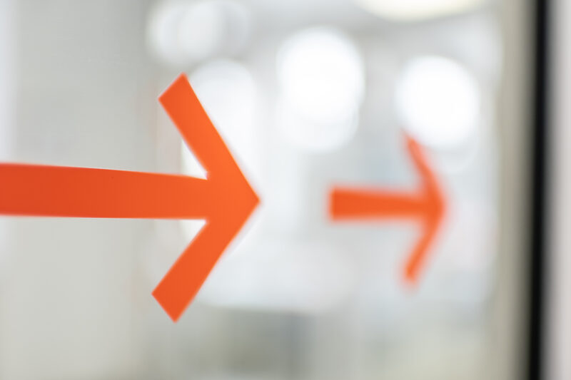 Photo of two orange arrows on a glass door.