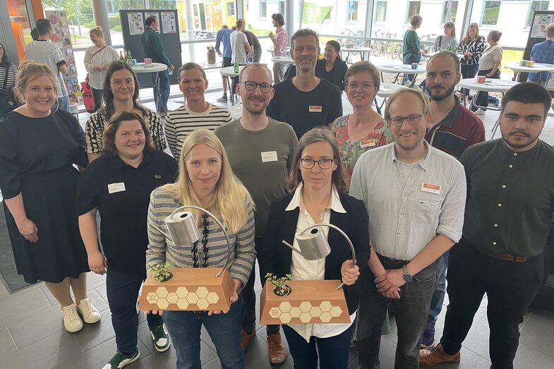 A group of people, including the two prizewinners with trophies in their hands