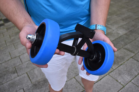 One person holds two rollers in their hands, which are connected via an axle.