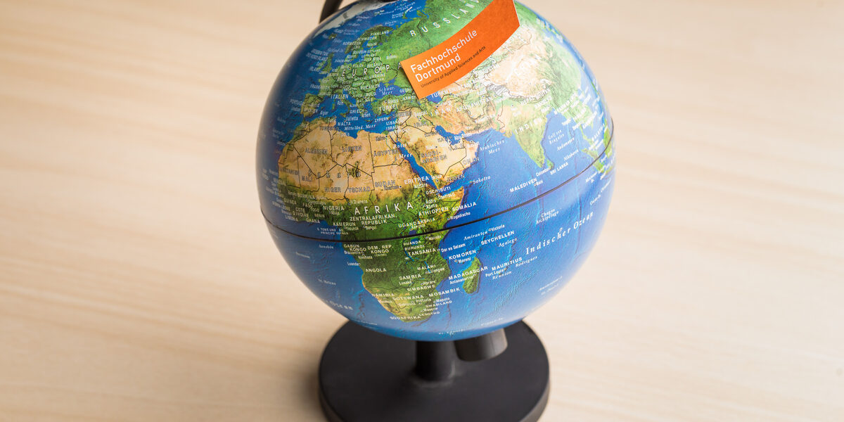 Photo of a globe with a note with the FH word mark stuck to it.