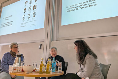 People talking to each other in front of a screen in a lecture hall.