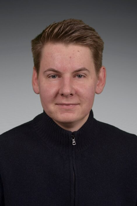 A person with blond hair and a dark sweater against a gray background looks calmly into the camera. (Photo: private)