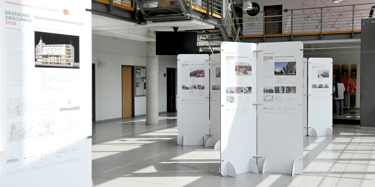 Exhibition in the foyer of the faculty with free-standing white panels presenting architectural projects for the German Brick Award 2024.