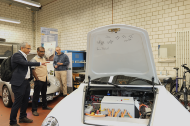 Three people stand between several cars in a laboratory at the Faculty of Mechanical Engineering.