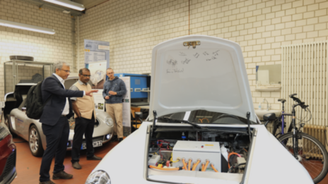 Drei Personen stehen zwischen mehreren Autos in einem Labor am Fachbereich Maschinenbau.