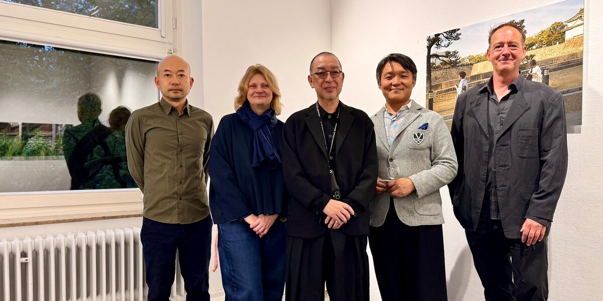 Fünf Personen in einem Innenraum schauen freundlich Richtung Kamera.