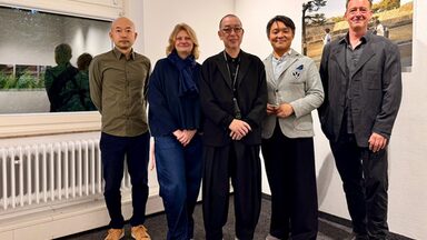 Fünf Personen in einem Innenraum schauen freundlich Richtung Kamera.