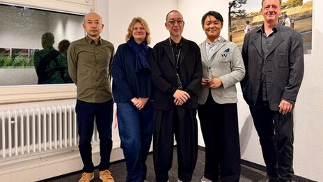 Fünf Personen in einem Innenraum schauen freundlich Richtung Kamera.