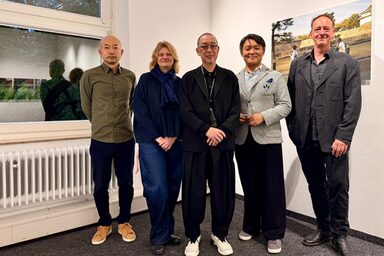 Fünf Personen in einem Innenraum schauen freundlich Richtung Kamera.