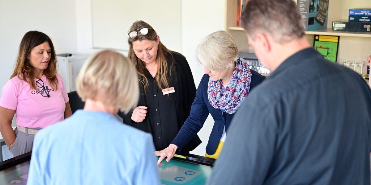Several people are standing around a table whose surface is a touchscreen.