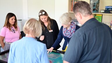 Several people are standing around a table whose surface is a touchscreen.