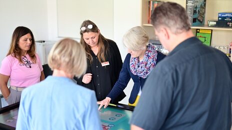 Mehrere Menschen stehen um einen Tisch herum, dessen Oberfläche ein Touchscreen ist.