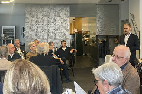 Menschen sitzen an Tischen und unterhalten sich.