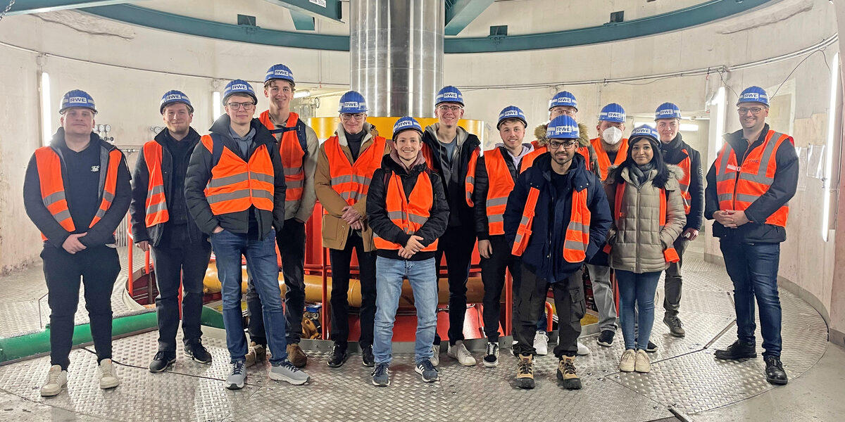 A group of people wearing high-visibility vests and helmets stand in a round building.