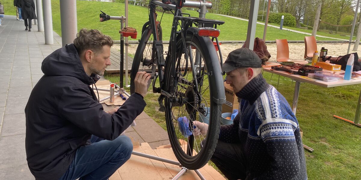 Two people are working on a bicycle at the FH Emil-Figge-Straße campus.