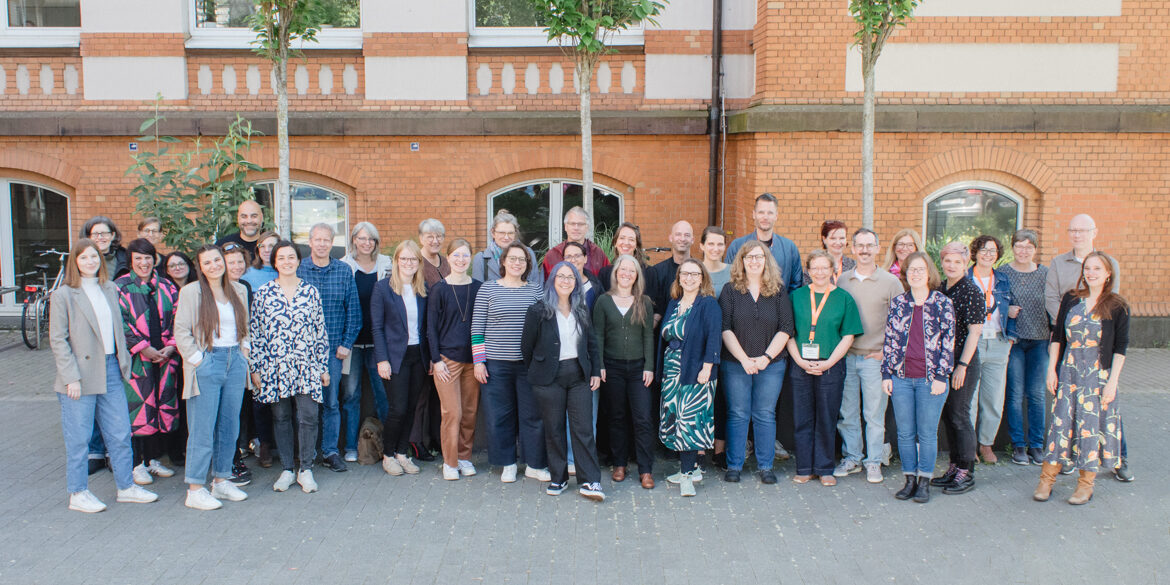 Participants of the "BAG Prax" conference stand in a group picture in the inner courtyard of Sonnenstraße