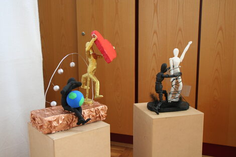 Two so-called Nana sculptures, each on a pedestal at an exhibition