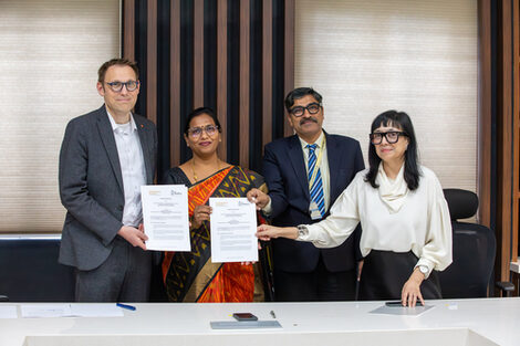 Mehrere Personen halten unterschriebene Verträge in die Kamera.