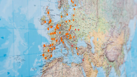 Close-up of a world map on which places are marked with orange dots.