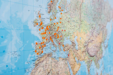 Close-up of a world map on which places are marked with orange dots.