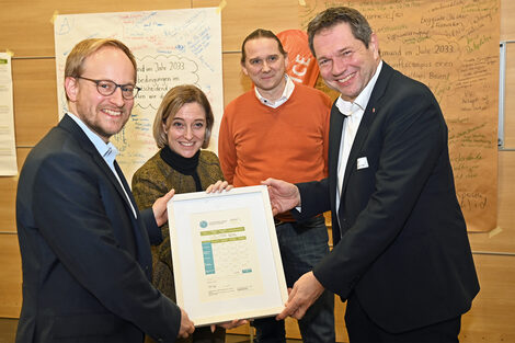 Four people hold a certificate