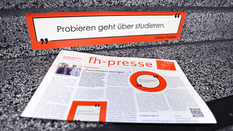 Eine fh-presse liegt auf einigen Treppenstufen. Auf denen ist eine Aufkleber mit einem Energiesparhinweis platziert.