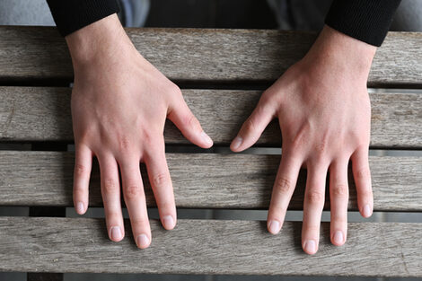 Close-up of a person's hands resting on a table.