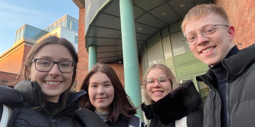 Four people are standing in front of a building.