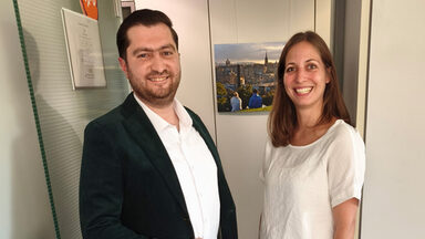 Two people are standing next to each other in front of an open door.