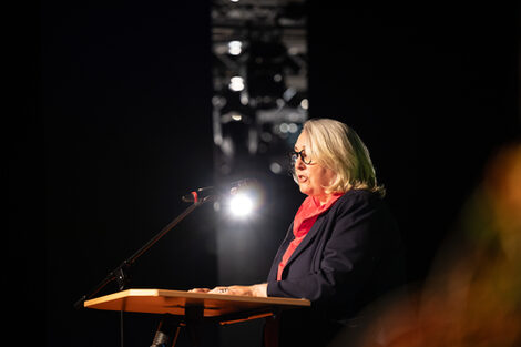 A person speaks at a lectern and looks to the left out of the picture.