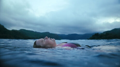 Eine Frau schwimmt mit dem Rücken in einem großen Gewässer.