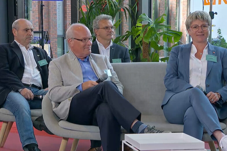 Drei männlich gelesene Personen und eine weiblich gelesene Person sitzen in einem TV-Studio auf zwei Sofas.