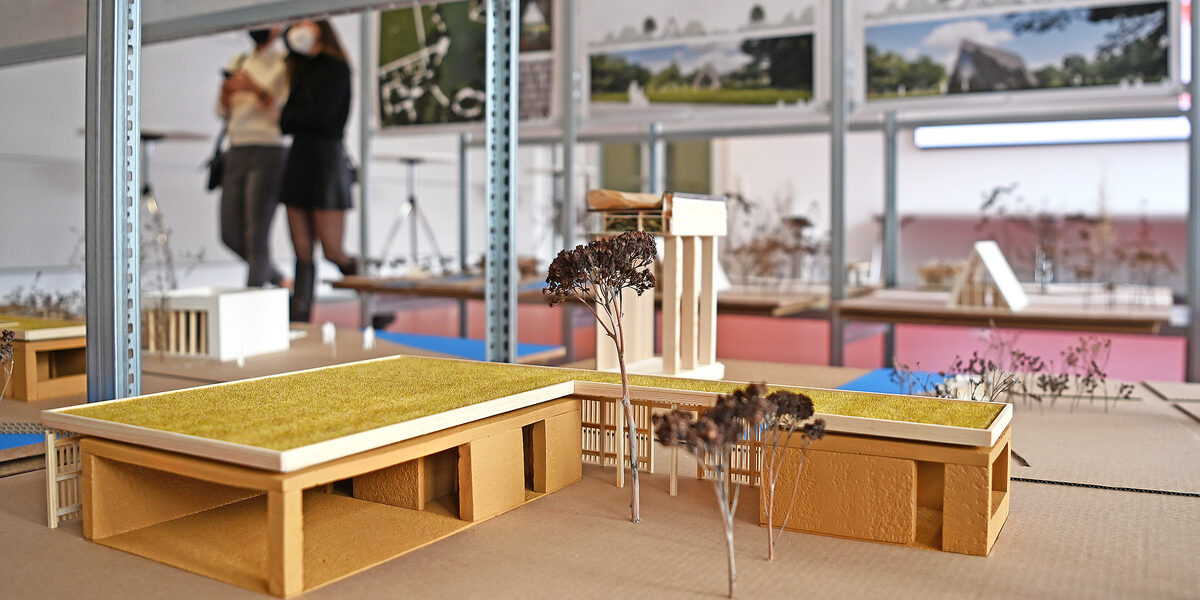 Ein Architekturmodell steht in einem Ausstellungsregal im Baukunstarchiv NRW in Dortmund. Im Hintergrund sind unscharf weitere Zeichnungen und Skizzen zu sehen.
