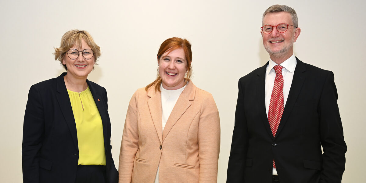 Three people against a white background look smiling into the camera.