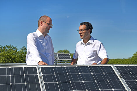 Zwei Personen stehen auf dem Dach der FH Dortmund an der Solaranlage und unterhalten sich.