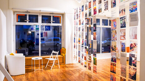 A wall of transparent transparencies, on which photos of past events have been printed, hangs in the middle of the room.