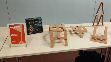 On a table stands a small Leonardo bridge consisting of forty equally sized wooden panels