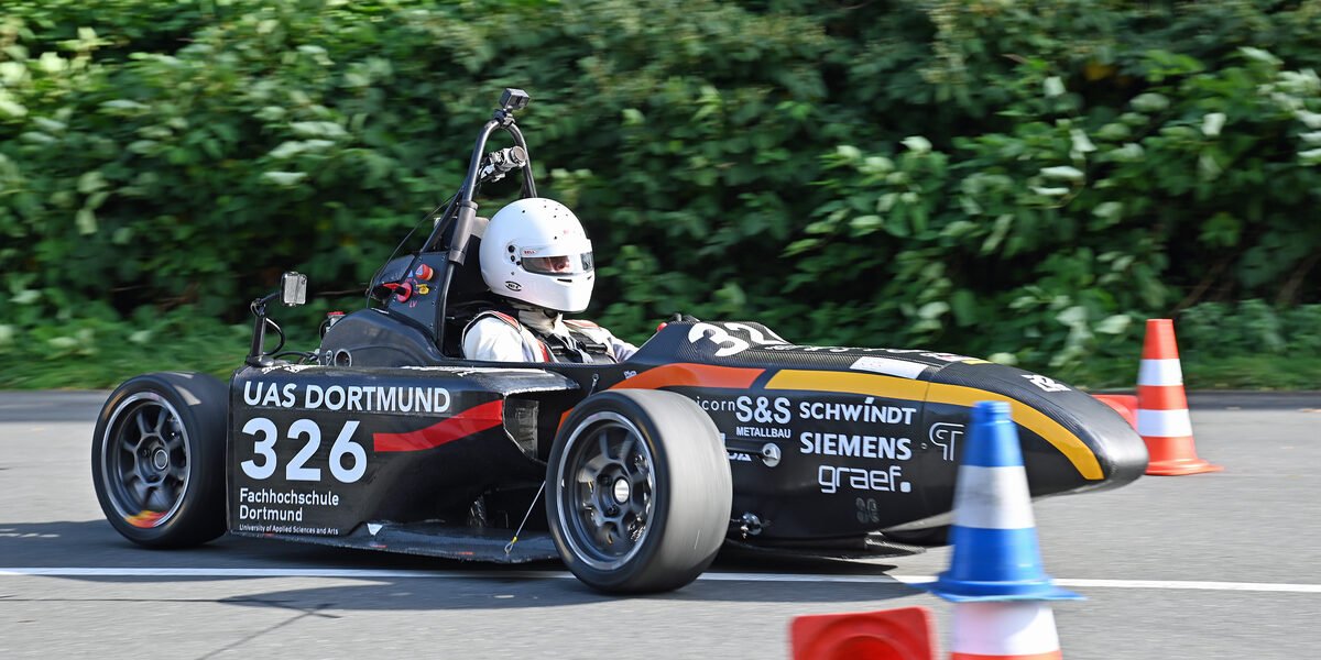 A racing car from Fachhochschule Dortmund drives on a race track.