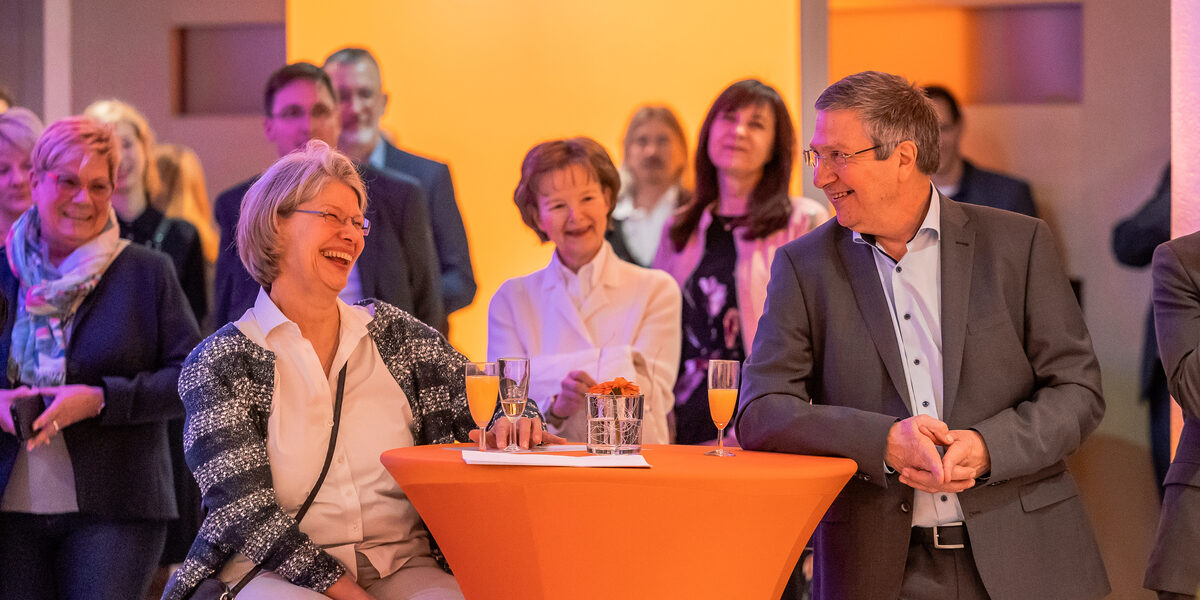 A group of people are standing around a table. They are all laughing heartily.