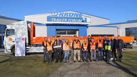 Several people are standing in front of a large truck.