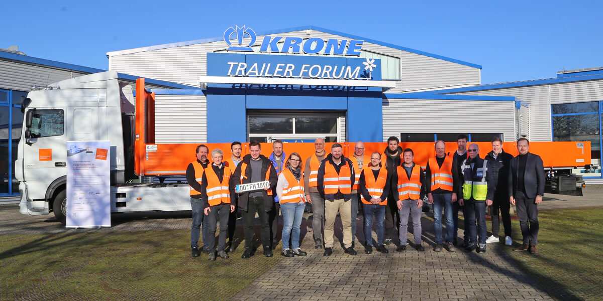 Several people are standing in front of a large truck.