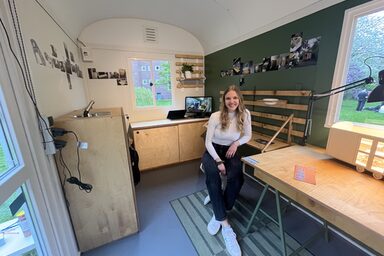 A female figure sits in a converted construction trailer.